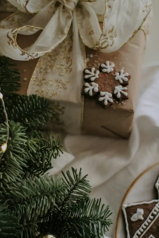 A wrapped Christmas gift with ivory ribbon and evergreen branches